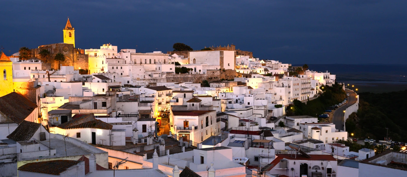 Vejer illuminé au crépuscule, avec son église et son château dominant le village